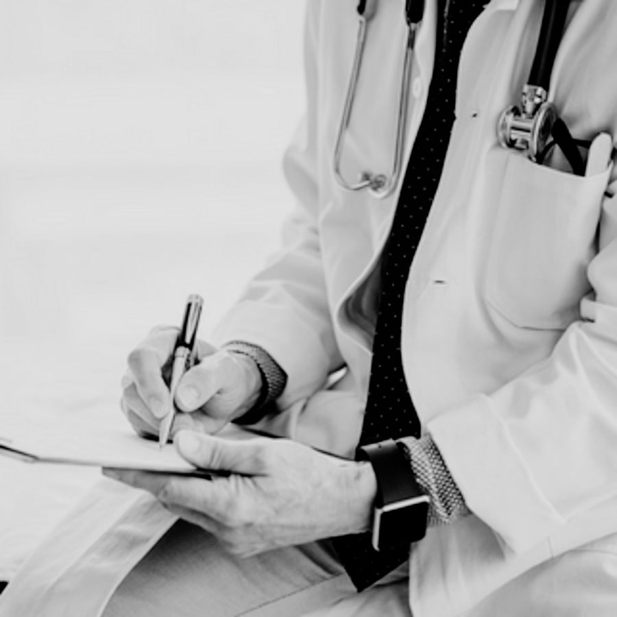 A black and white photo of a doctor writing on a piece of paper